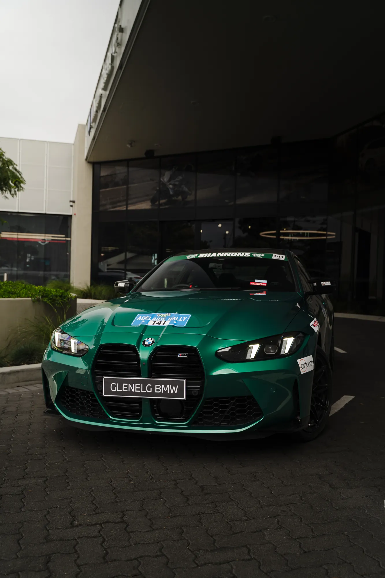 A racing green BMW M4 head-on outside the Glenelg BMW showroom