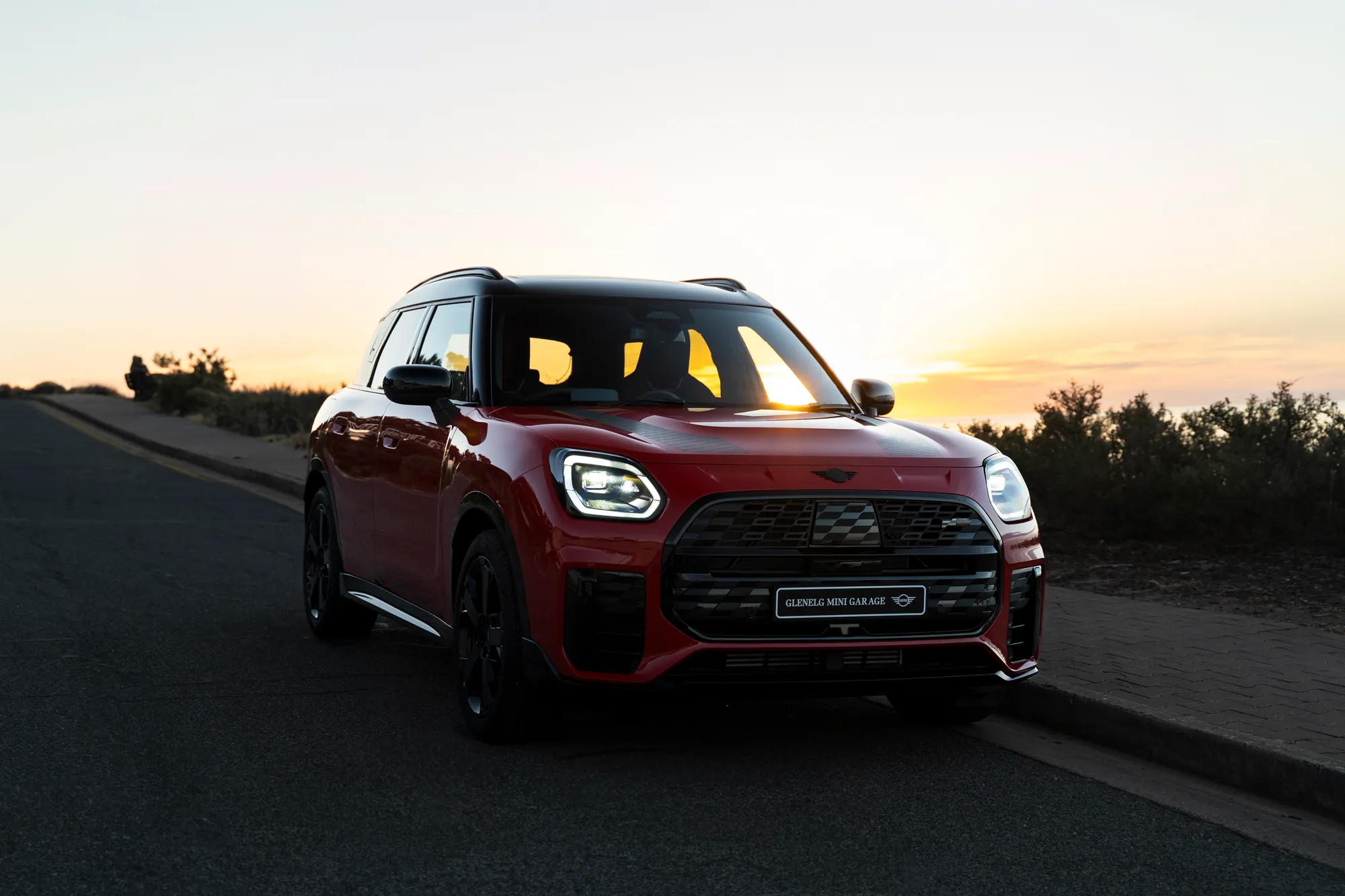A red MINI Countryman John Cooper Works head-on at sunset