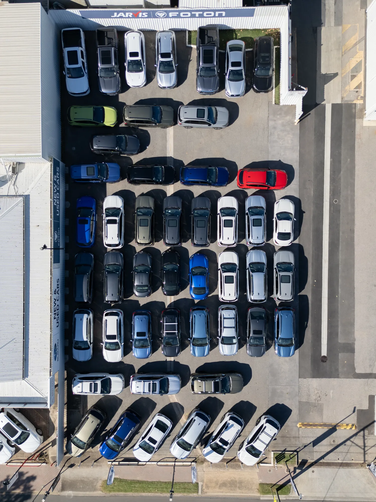 Overhead drone frame of the Jarvis dealership forecourt, rows of new cars