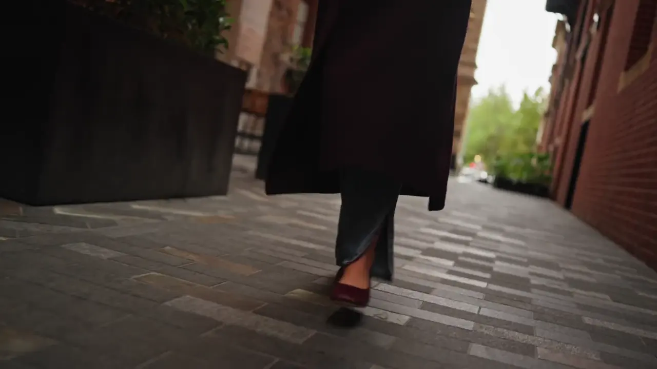 Burgundy heels and a long coat walking a brick laneway, from the Penn Shoes autumn campaign film
