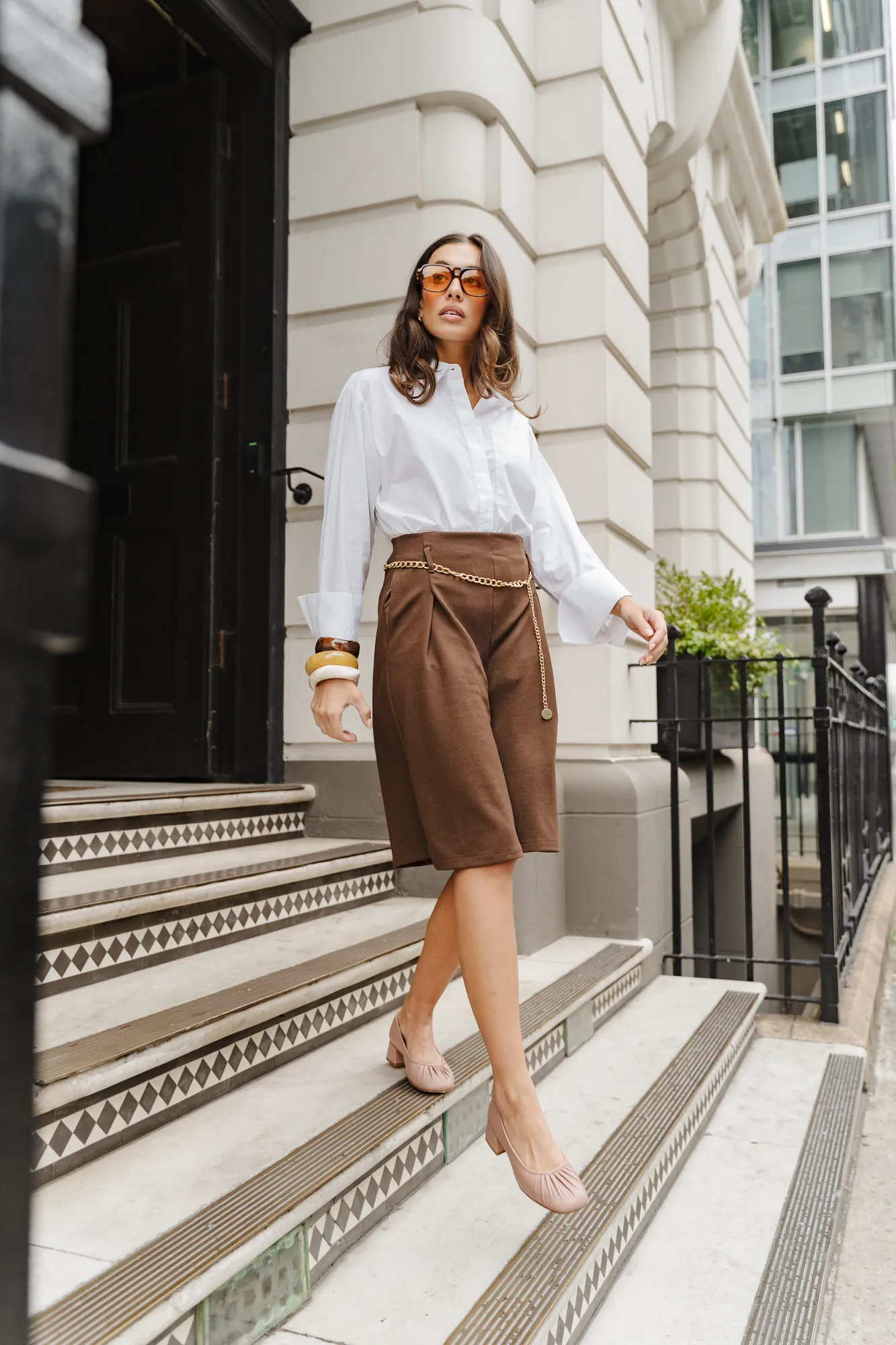 Penn Shoes autumn campaign: white blouse, brown wrap skirt and nude heels on stone steps