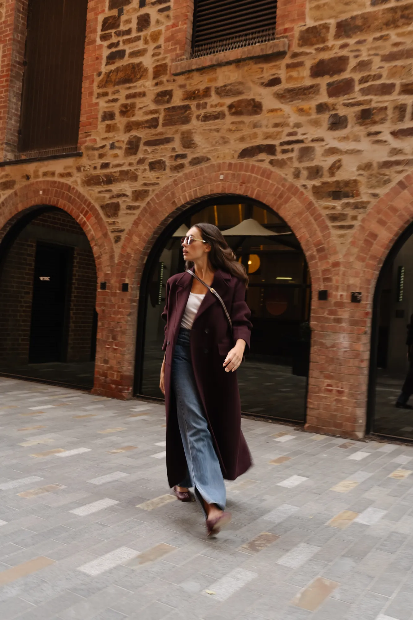 Penn Shoes autumn campaign: long plum coat and heels under brick archways