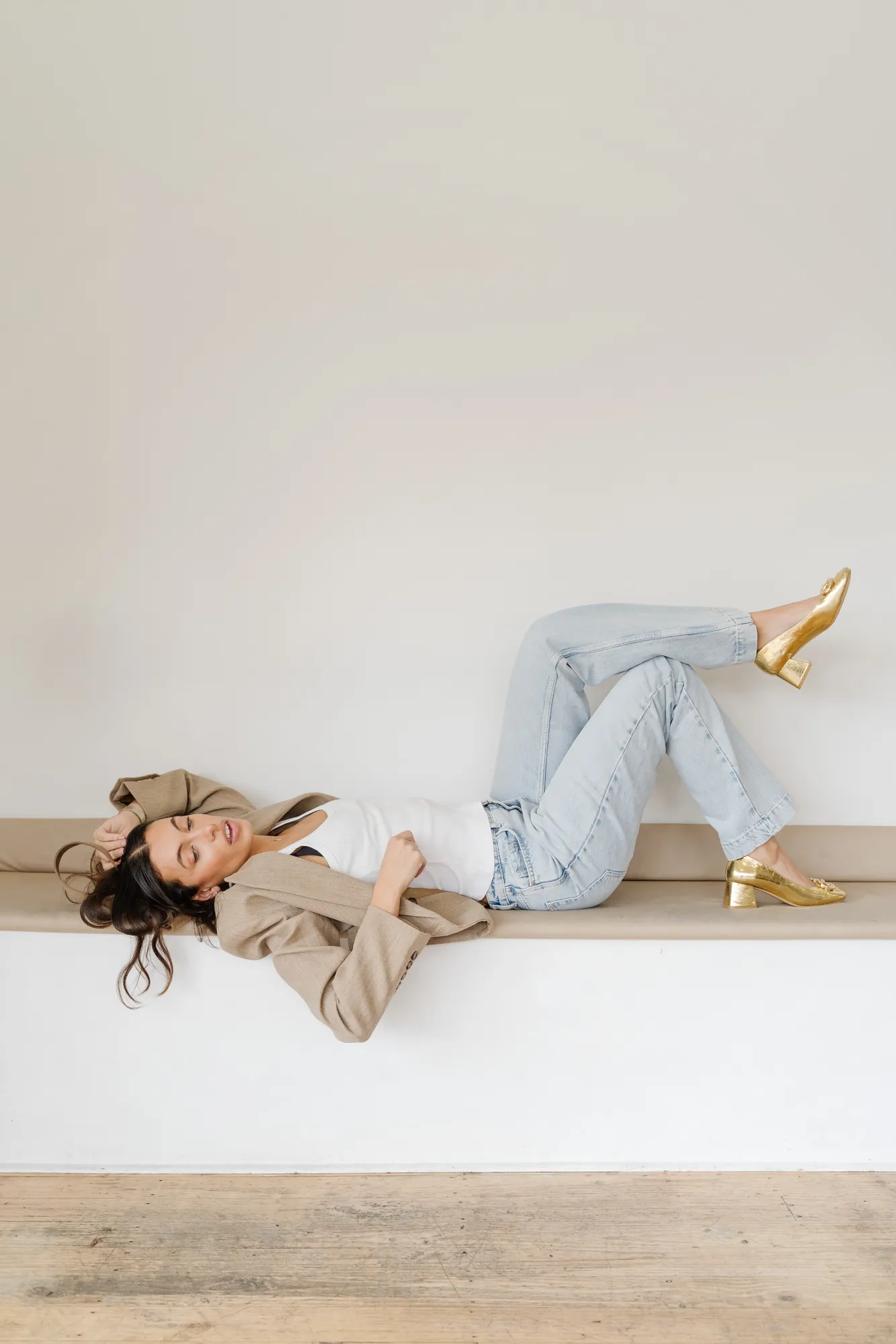 Penn Shoes campaign: reclining on a bench in a beige set, gold metallic heels