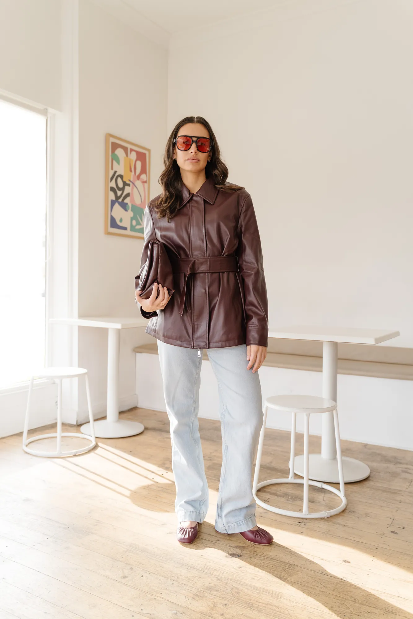 Penn Shoes campaign: brown leather jacket and jeans in a sunlit cafe