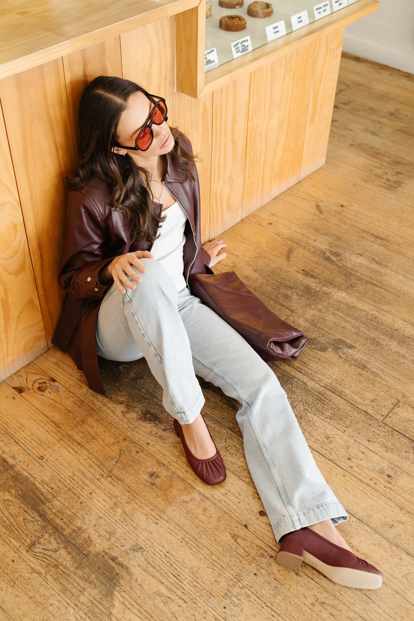 Penn Shoes campaign: seated against a timber counter in burgundy loafers