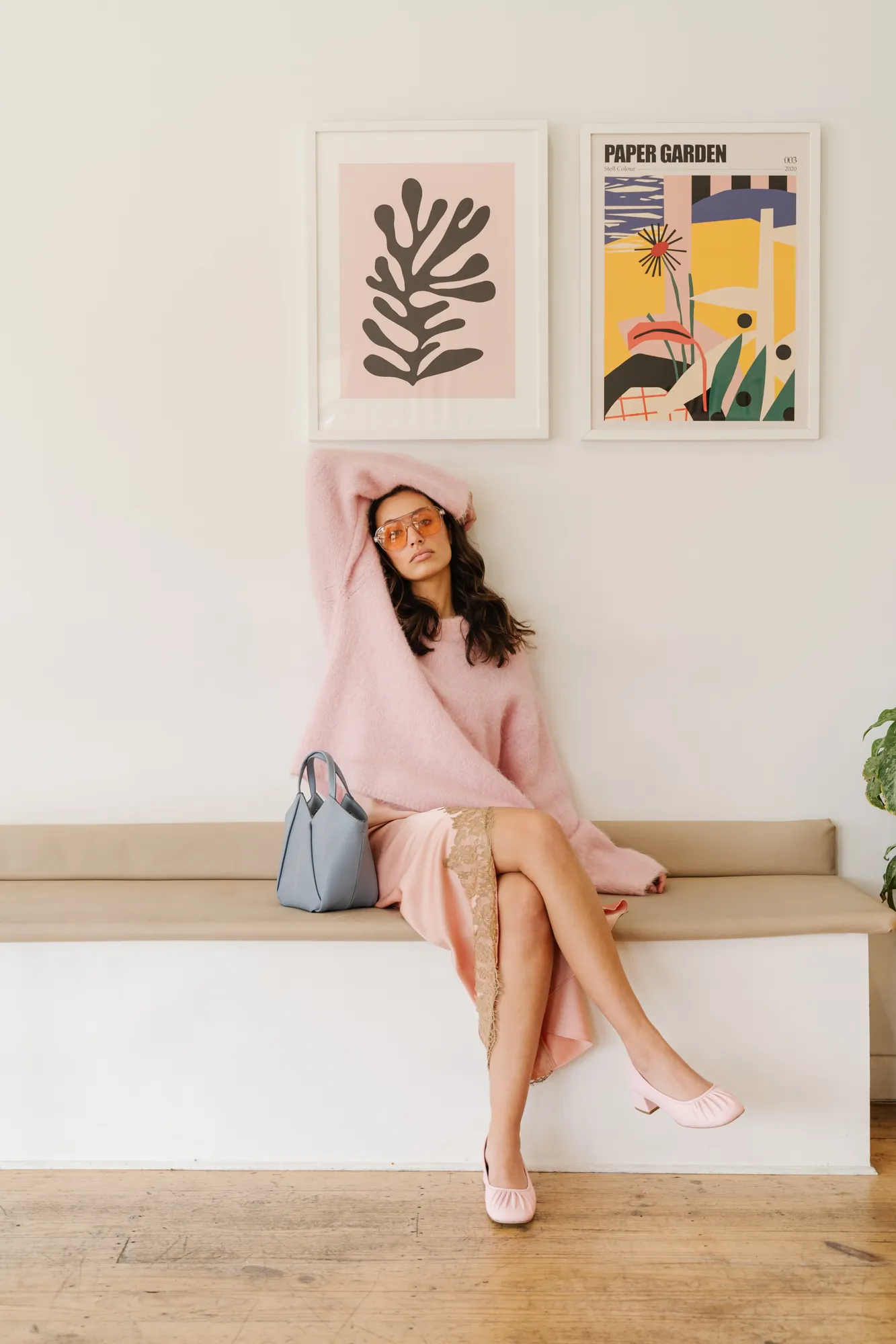 Penn Shoes campaign: pink knit and pink flats, seated with a blue handbag